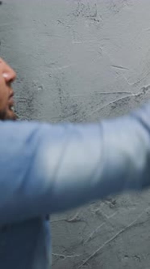 Black Guy in Denim Shirt Paints Corner with Brush in Room