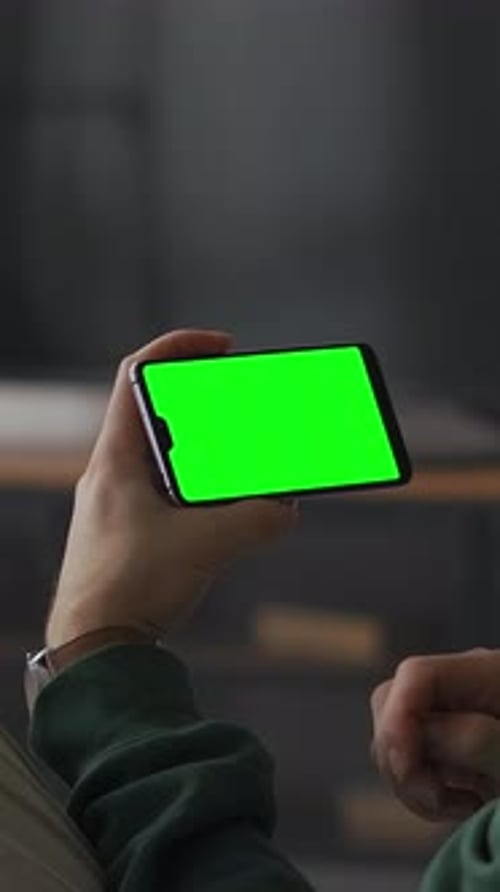 Person Holding Smartphone with Bright Green Chroma Key Screen in Horizontal Orientation Ready for