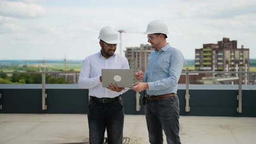 Two Construction Engineers Discussing Project Data on Rooftop Site