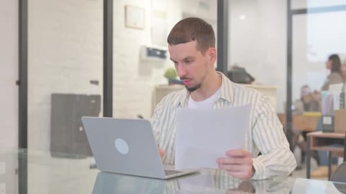 Man working with laptop and documents in office
