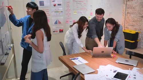 Two young business man and woman discuss about the project on board and other co-worker in office