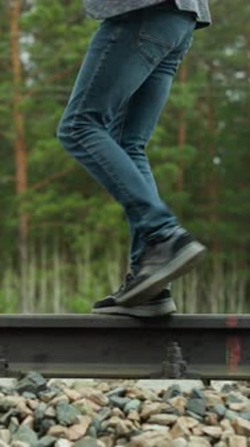 Man Walking on Railroad Tracks Through Forest