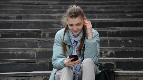 Young Woman Using Phone on Concrete Urban Stairs