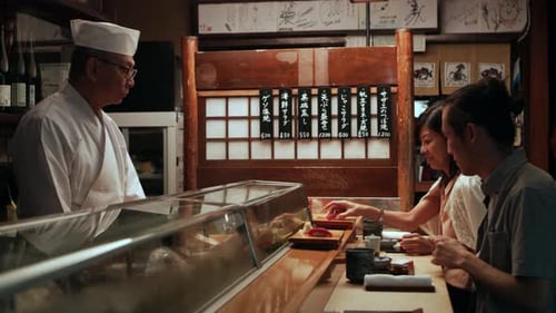 Sushi Chef Serving Customers in Traditional Restaurant