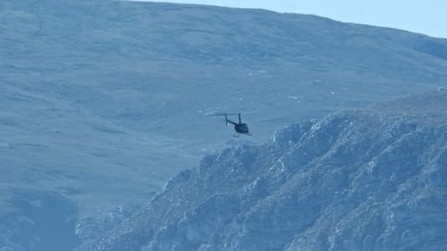 A helicopter flies with a huge mountain in the distance
