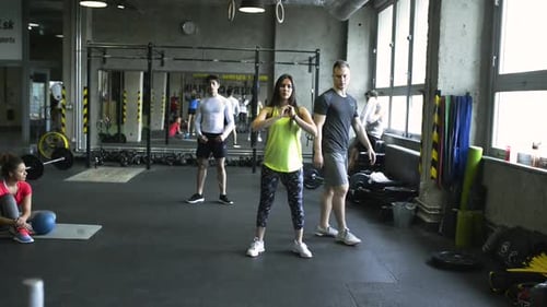 Young Woman in Crossfit Gym with Coach Doing Squats