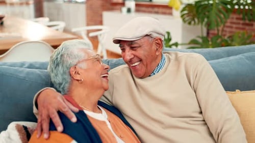 Senior Couple Laughing Together Cuddled on Sofa