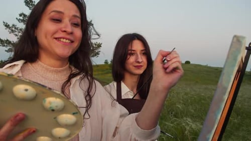 Women Painting Together in a Green Field