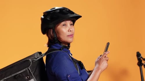 Woman in Helmet Checks Smartphone for Delivery