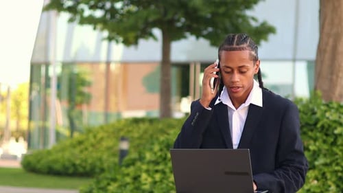 Young Adult Using Laptop and Phone Outdoors