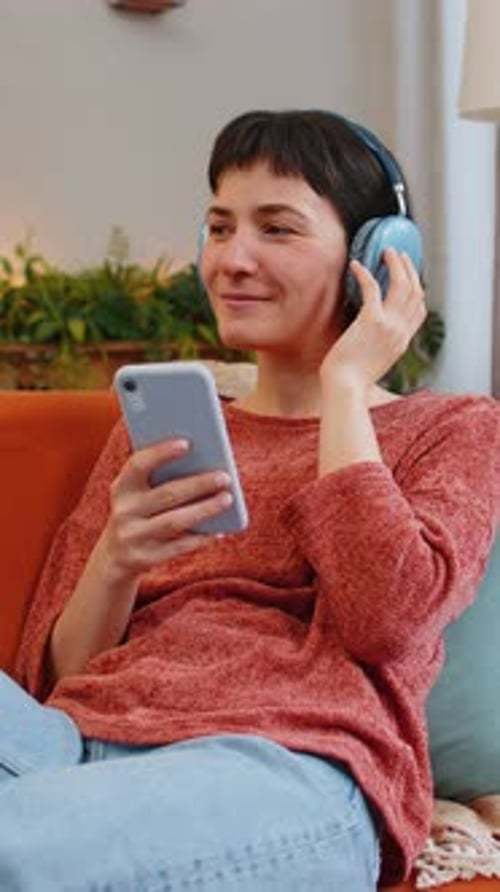 Woman Relaxing On Sofa Listening To Music