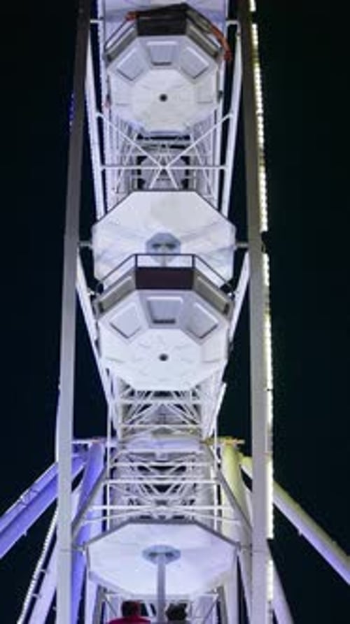View of an illuminated ferris wheel on the beach in the evening in Antibes, France. Vertical