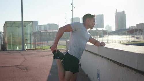 Man Stretching Leg in Urban Setting