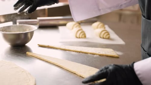 Baker Sprinkles Flour on Croissant Dough Indoors