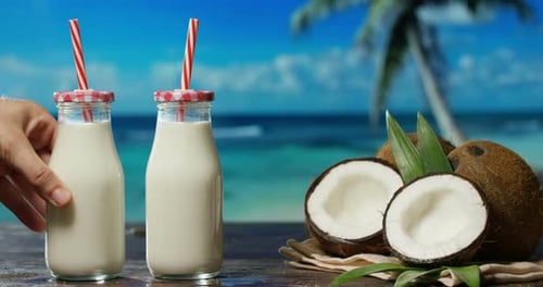 Delicious fresh nutritious coconut milkshake on the background of the sea, palm and sky, the conce