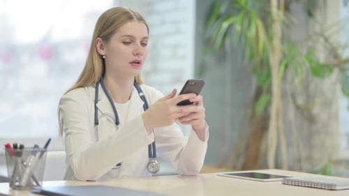 Young Doctor Browsing Smartphone in Clinic