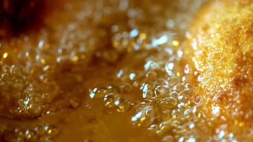 Macro Shot of Breaded Food Deep Frying in Bubbling Golden Oil