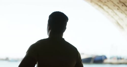 Silhouette of Man Stands Under a Bridge Looking Out