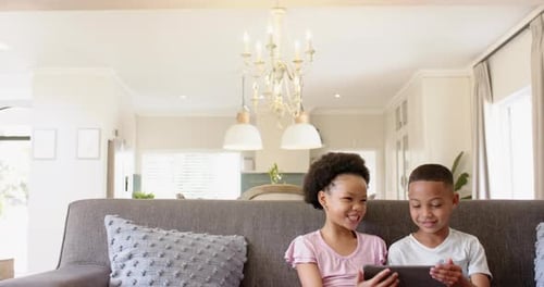 Children Enjoying Tablet Together on Sofa Indoors