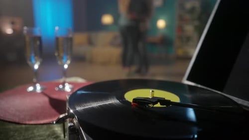 Vintage Turntable with a Spinning Vinyl Record Close Up on a Blurred Background of a Couple Dancing