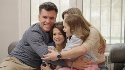 Family Embraces on Couch in Home
