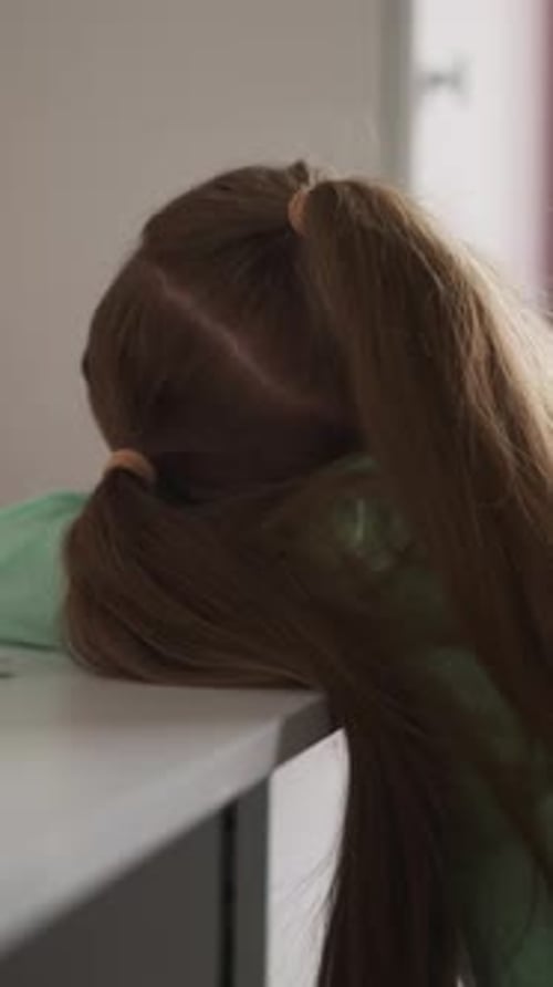 Tired Girl with Ponytail Lies on Desk with School Supplies