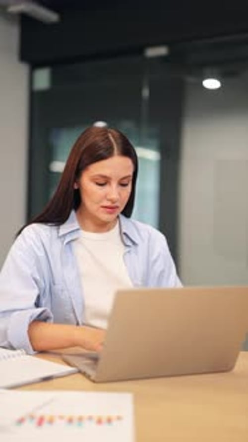 Young Woman Working Diligently on Laptop in Modern Office