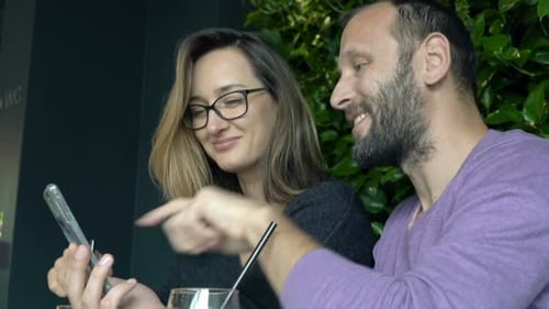 Young Couple with Smartphone Talking and Drinking Beverages Sitting in Cafe Adult