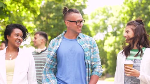 Smiling friends walking and talking in a green park