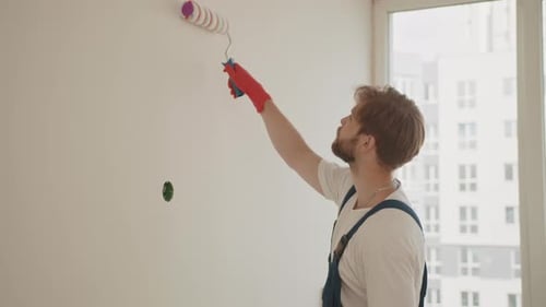 Bearded Young Adult Painting Wall with Roller