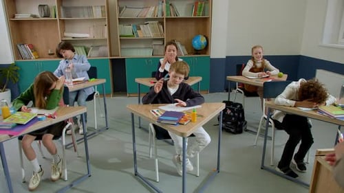 Elementary School Class Children Communicate with the Teacher Answering Question