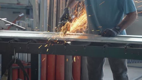 Das Innere einer schweren Maschinenbauanlage mit einem Industriearbeiter, der eine Winkelschleifmaschine einsetzt