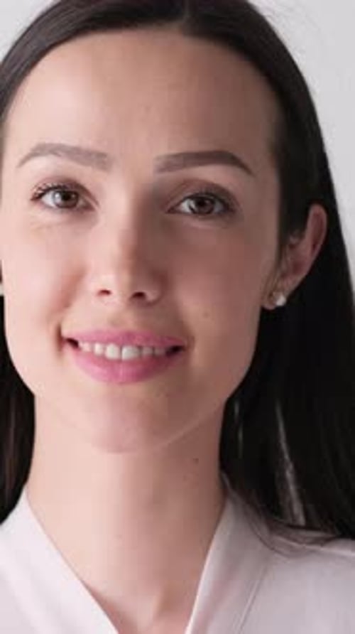 Portrait of a Beautiful Brunette Woman on a Gray Background in the Studio Vertical Video