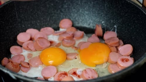 Cooking delicious and nutritious scrambled eggs and sausages for breakfast.