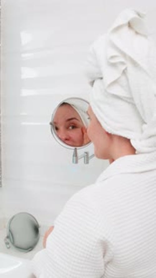 Woman in Robe Applies Cream to Face