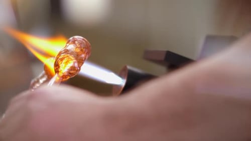 Glaspfeife, die von einem Glasbläser in der Fackelflamme erhitzt wird, Nahaufnahme