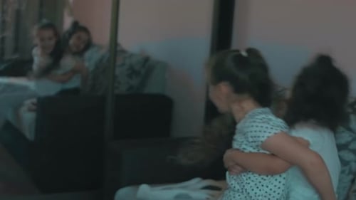 Two Happy Girls Embrace in a Bedroom