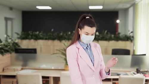 Young girl in the office sprays antiseptic on his hands and washes thoroughly