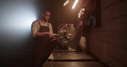 Male Worker Operating Lathe Machine in Dark Garage