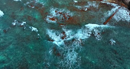 Turquoise waters of the Pacific Ocean. White foamy waves roll to the shore. Aerial view.