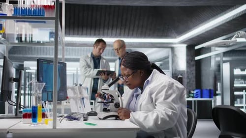 Mulher trabalhando com microscópio e bandeja de amostra no laboratório de química