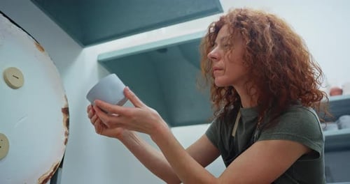 Woman Inspecting Handmade Ceramic Mug in Studio