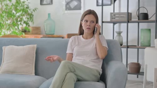 Upset Woman Talking on Phone on Couch