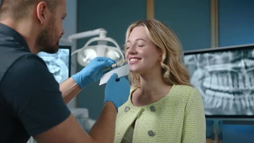 Medium Close Up of Male Dentist and Female Patient Selecting Artificial Teeth