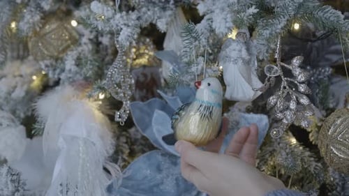 Placing Bird Ornament on Snowy Christmas Tree