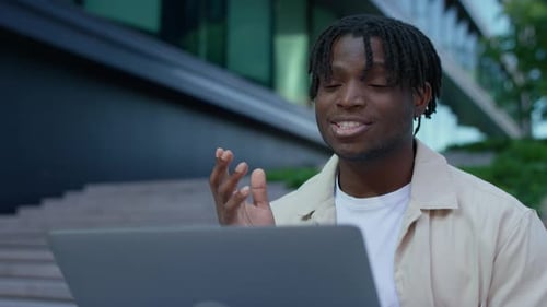 Man Videoconferencing Outdoors Using Laptop in City