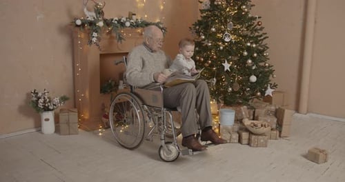 Grandfather Reads to Grandchild by Christmas Tree
