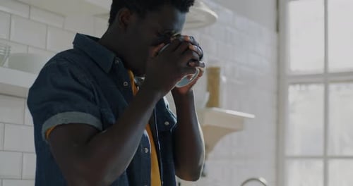Young Adult Drinking From Mug in Bright Kitchen
