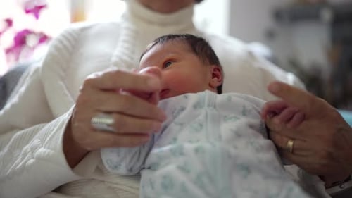 Grandmother Holding Newborn Grandchild Comforting and Cuddling