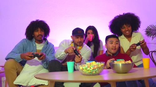 Party für Erwachsene. Attraktive junge Männer sitzen auf dem Sofa und spielen Videospiele mit Popcorn. Mit der Freude